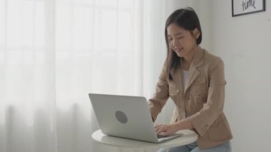 Young asian businesswoman working on laptop computer on desk at home office, freelance looking and typing on notebook on table, lifestyles of woman studying online, business and education concept.