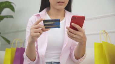 Kanepede oturan, internet üzerinden akıllı telefon alışverişi yapan, internete kredi kartı alan, alım-satım, ödeme ve iş konseptiyle ödeme yapan mutlu bir kadının elleri..