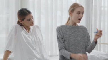 Happiness young caucasian woman taking pregnancy test while excited and satisfied with friends in the bedroom at home, happy mother with smile and expression with love, ovulation and maternity.
