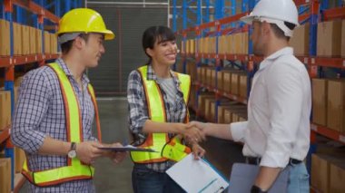 Grup mühendisi, yönetici işçiyle konuşurken ve fabrikadaki depoda başarı anlaşması imzalarken ortak ve yönetici el sıkışma, nakliye ve lojistik konseptle tebrik ediyor..