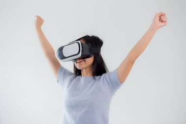 Young asian woman wearing vr headset playing game with excited in the bedroom at home, female using virtual reality or metaverse innovation for simulation 3D, lifestyles and technology concept.