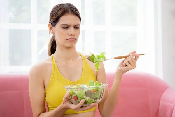 Jovem Caucasiana Sentada Sofá Comendo Salada Legumes Enquanto Sente Desgostosa — Fotografia de Stock