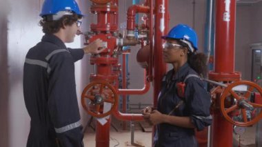Young woman and man engineer check and examining pipeline and discussion in the factory, mechanic or technician inspector plumber valve and talking together, industrial and maintenance concept.