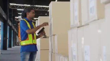 Delikanlı, fabrikadaki depoda nakliye ve dağıtım için kutu destesi taşıyor. Depoda çalışan işçi, lojistik ve ulaşım, endüstriyel ve kargo konsepti..