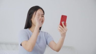 Genç Asyalı bir kadın, internet üzerinden arkadaşlarıyla video konferans için akıllı telefon kullanıyor. İş kadını, sosyal ağla görüşmek için telefon görüşmesi yapıyor. Akıllı telefon, iş ve iletişim kavramı..