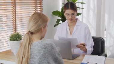 Young woman doctor talking and discussion with patient about disease and illness for diagnostic at clinic, physician explaining and consultation about sick and looking document, medical concept.