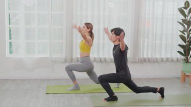 Genç Asyalı erkek ve kadın yoga yapıyor ve kaslı elleri uzatıyorlar ve evde paspasın üzerinde birlikte sağlık için geri dönüyorlar, vücut esnekliği, spor konsepti ve vücut esnekliği için çift yoga eğitimi yapıyorlar..