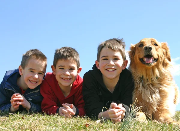 Niños acostados en la hierba con el perro — Foto de Stock