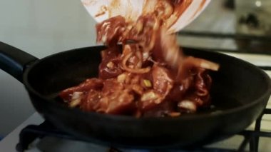 Kaybet kendini. Bir adam ev mutfağında domates sosunda et kızartıyor. Aşçı eti ahşap bir spatulayla tavada karıştırır..