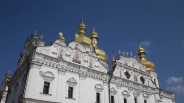 Kiev-Pechersk Lavra. Bulutlu açık mavi gökyüzüne karşı altın kubbeleri olan güzel bir kilise. Kamera hareketi