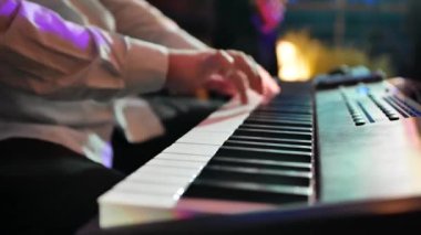  Bir konser ya da parti sırasında güzel arka planda sentezleyici çalan bir adamın yakın çekimi. Parmaklar ritmik olarak elektrikli piyanonun tuşlarına basar. Yavaş çekim