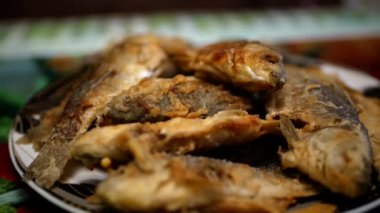 İştah açıcı kızarmış haç balığı tabakta yatıyor, kamera dairesel hareket ediyor.