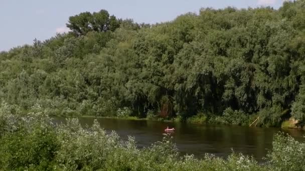暑い夏の日には 2人の高齢者がマットレスとサンバスで川に浮かんでいます — ストック動画