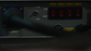 Taklacıları çalıştıran bir adamın elinin yakın plan çekimi. Genç adam kırmızı ışıkta parlamaya başlayan ekipmanı açmak için düğmelere basar..