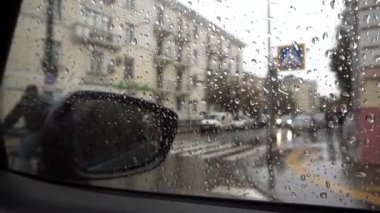 Arabanın camından çekiyoruz. Yağmurlu bir günde yolda ilerleyen bir bisikletçinin arka planına karşı bir arabanın camındaki damlacıklara odaklanın..