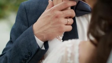 Genç gelin ve damat sarılıp birbirlerinin ellerini tutuyorlar. Yeni evliler birbirlerinin ellerini okşarlar..