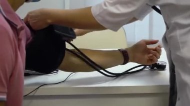 Doktor, tonometreyi hastanın koluna koydu. Klinikteki hastaya uygulanan basıncın ölçümü.