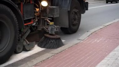 Sokak temizleme makinesi şehir caddesini fırçalarla temizliyor. Sokakları ve yol yüzeylerini temizlemek için ekipman. Sonbahar sokağından dökülen sarı yaprakları temizleyen makine fırçası.