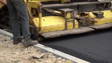 Kamu işçileri asfalt kaldırımın arkasında asfalt biriktiriyor. Yeni bir asfalt beton yol inşaatı.