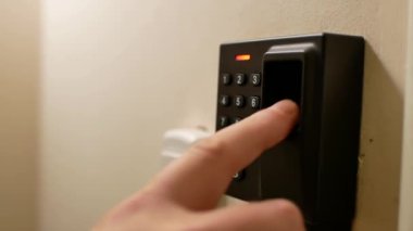 Kapıları açmak için parmak izi sensörünü kullanan bir adamın yakın çekim videosu. Bir adam biyometrik sensör kullanarak bir kapı kilidini açıyor..