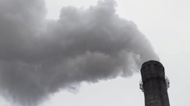Bir termik santralin bacasından bulutlu bir gökyüzünün arka planına doğru çıkan dumanın yakın plan görüntüsü. Bir endüstriyel fabrikanın bacasından çok fazla duman çıkıyor..