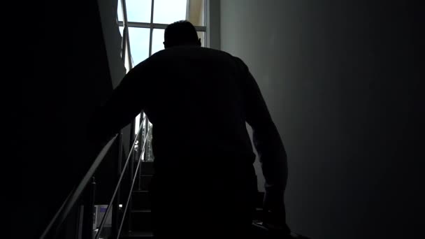 スローモーションで 窓に背を向ける男は オフィスやホテルで外交官を手にして階段を登る 仕事の考え方 — ストック動画
