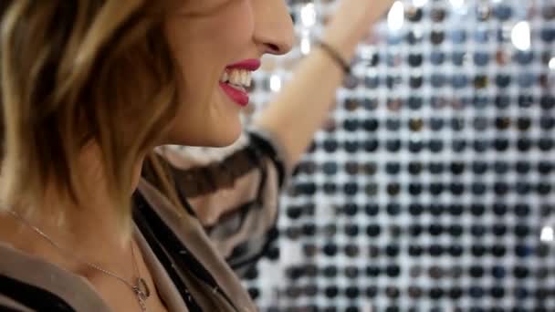 壁に輝く鏡のペンダントに沿って彼女の手を実行する若い美しい少女のクローズアップビデオ撮影 写真セッション中に甘く微笑む写真モデルのビデオポートレート — ストック動画