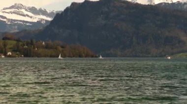 Yelkenli yatlar ve gemiler, karla kaplı güzel dağların arka planına karşı gölde yelken açarlar. Güzel bahar manzarası. Lucerne Gölü, İsviçre, Avrupa.