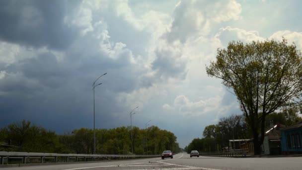 美しい雲が青い空を横切って 車がすぐに運転する長い高速道路を横切って移動します 雨の雲が近づいている 4Kビデオ時間の経過 — ストック動画