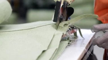 Tekstil işçisi sıkı bir kumaşı el makasıyla kesiyor. Dikiş fabrikası