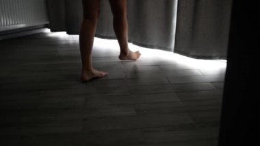 Genç bir kızın seksi bacakları parke zemine basıyor. Cüppeli ve uzun peçeli gelin pencereye gelir ve perdeleri açar..
