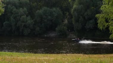 Bir yaz günü, bir motorlu tekne nehir boyunca yüzer ve bir insanı su tahtasına ya da sörf tahtasına sürükler. Gemi bir adamı su kayağına bindirir..