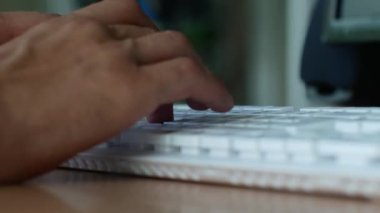 İş günü, erkek ellerinin ofiste beyaz bir klavyeye yazı yazışlarını yakından çek. Erkekler klavye tuşlarına basar.