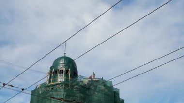 Two male construction workers are repairing the roof of a beautiful building during restoration.