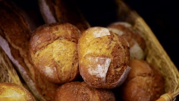 新鮮な食欲をそそるパンはウィッカーバスケットにあります 焼きたてのクリスピーパンに小麦粉のクローズアップが振りかけられます カメラの回転 — ストック動画