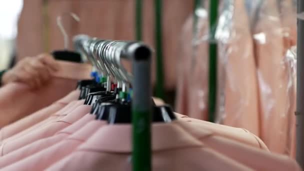 一个服装厂工人的特写镜头 他在一个手推车上挂着许多新的粉色彩色运动衫 许多新夹克 — 图库视频影像