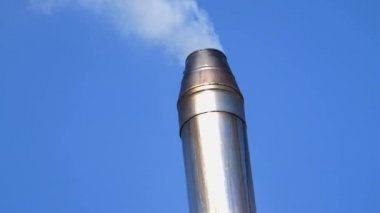 Paslanmaz çelik borudan çıkan duman. Bir kır evinin baca borusu. Katı yakıt ısıtma, alternatif yakıt, biyoyakıt. Hava kirliliği