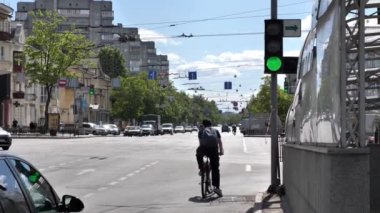 Ukrayna Chernihiv 2022: Trafik ışığı kontrolündeki kavşakta bir bisikletçi ve arabalar. Trafik ışığı yeşile döner ve bisikletçi sağa döner. Şehir araç trafiği.