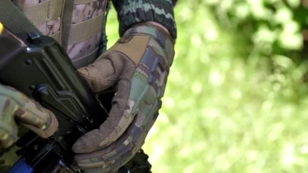 一名乌克兰武装部队成员在巡逻或作战行动中手持一支卡拉什尼科夫冲锋枪 一个戴着战术手套拿着自动武器的军人的手士兵 — 图库视频影像