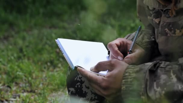 ทหารเข ยนจดหมายขณะน งอย บนหญ าหน ของกองก ดอาว ธของย เครนจดบ กในสม — วีดีโอสต็อก