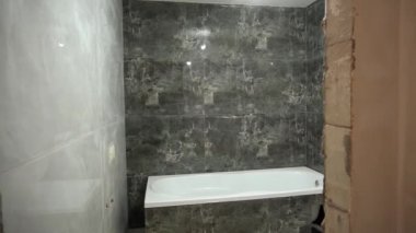 Tadilat sırasında boş bir banyo. Yeni bir küvet kuruldu, duvarlara yeni seramik fayanslar yapıştırıldı..