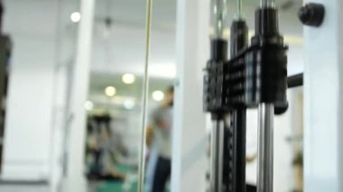 Yakın plan çekim. Egzersiz makinesindeki metal nesneler yukarı aşağı hareket ediyor. Spor salonunda egzersiz yaparken spor yapmak için egzersiz makinesi..
