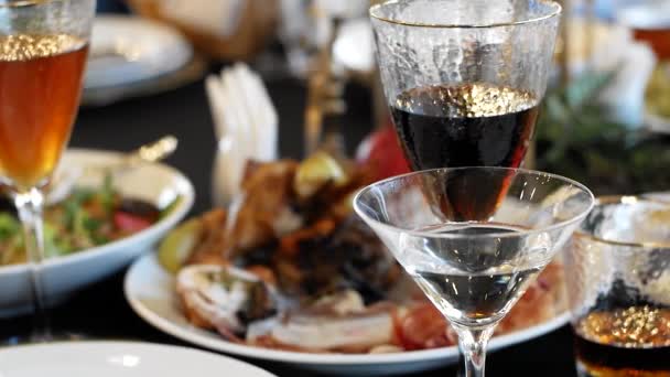 餐桌上有食物和饮料 一杯葡萄酒 一杯香槟和一杯威士忌 还有沙拉 肉和各种食物 — 图库视频影像