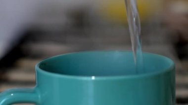 Bir erkek ya da kadın bir fincan çay, kahve ya da kakaonun içine çok sıcak su döker. Ev mutfağında sıcak bir sabah içkisi hazırlıyorum..