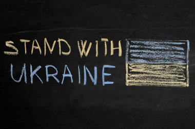 Üzerinde tebeşirle Ukrayna yazan bir yazı masası. Ukrayna bayrağı solda.