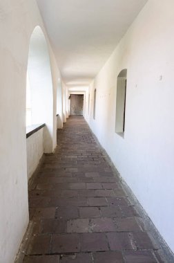 Beyaz duvarlarla kaplı dar bir balkon koridoru.