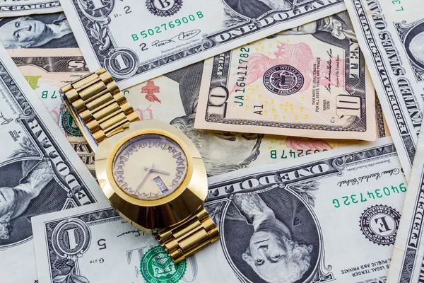 Wristwatch on a heap of paper dollars. — Stock Photo, Image