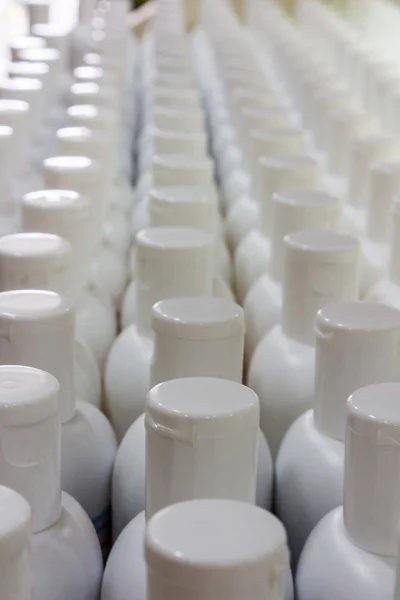 White plastic cream bottles in rows. — Stock Photo, Image