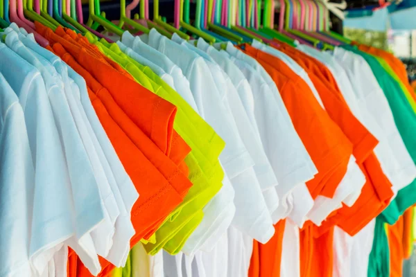 Variety of multicolored shirt clothes hangers in row. — Stock Photo, Image