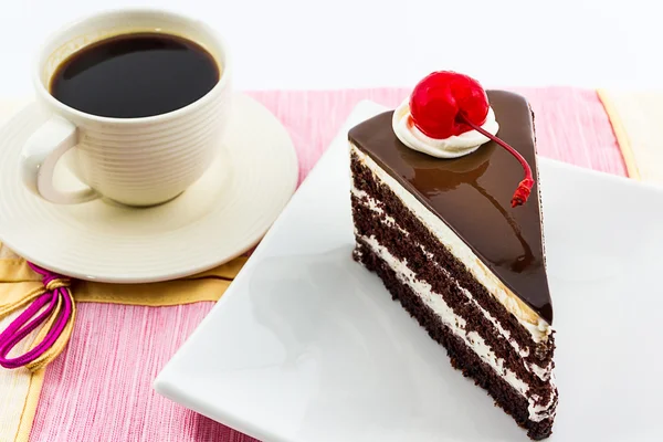 Fatia de bolo de chocolate com cereja vermelha e café . — Fotografia de Stock